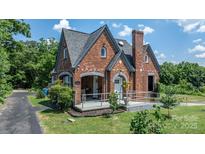 Charming brick home with unique architecture, lush landscaping, and a welcoming front porch at 115 12Th Sw St, Hickory, NC 28602