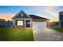 Charming single-story home boasts stone accents, inviting front porch, and well-manicured lawn at 1324 Secrest Commons Dr, Monroe, NC 28112