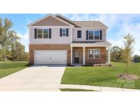 Charming two-story home with brick and siding exterior, a well-manicured lawn, and an attached two-car garage at 1332 Secrest Commons Dr, Monroe, NC 28112