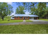 Charming brick home with a metal roof, long driveway, and mature trees in a serene setting at 2825 Old Pageland Marshville Rd, Wingate, NC 28174