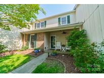 Charming townhome featuring a front porch with white chairs, lush landscaping, and traditional green shutters at 6809 Copernicus Cir, Charlotte, NC 28226