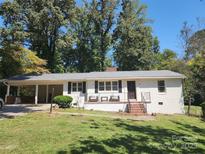 Charming brick home with a covered carport and welcoming front porch area and manicured yard at 148 Palaside Ne Dr, Concord, NC 28025