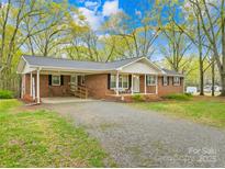 Charming brick ranch home with a carport and a spacious front yard surrounded by mature trees at 322 S Main St, Shelby, NC 28152