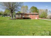 Expansive green backyard featuring a brick home with a wooden deck, and mature trees at 501 8Th Sw Ave, Conover, NC 28613