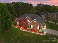 Beautiful brick home with a well-manicured lawn, a side-entry garage, and mature trees at 5629 Berry Ridge Dr, Harrisburg, NC 28075