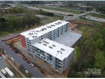 An aerial view of a modern apartment complex with a parking garage and nearby highway at 9901 Benfield Rd # 302, Charlotte, NC 28269