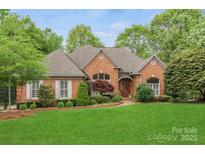 Charming brick home featuring manicured lawn, mature trees, and inviting curb appeal at 11424 Stonebriar Dr, Charlotte, NC 28277