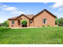 All-brick single-story home featuring a well-manicured lawn, mature landscaping, and classic architectural details at 121 Capstone Ct, Statesville, NC 28625
