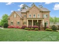 Brick two-story home with manicured lawn and colorful flowering shrubs accenting the facade at 13044 Fen Ct, Huntersville, NC 28078