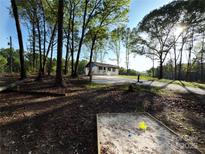 Charming single-story home surrounded by mature trees and a spacious yard. Features a sandbox in the foreground at 1407 Clarksville Campground Rd, Monroe, NC 28112