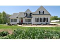 Charming white two-story home featuring a red front door, black shutters, and a well-manicured lawn at 16610 Blackberry Hills Dr, Midland, NC 28107