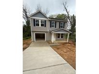 Two-story home with a gray exterior, black shutters, a covered porch, and a long concrete driveway at 204 Plyler St, Lancaster, SC 29720