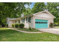 Charming white brick home with green shutters and a brightly colored turquoise garage door at 334 Hudson Dr, Harrisburg, NC 28075