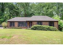 Charming brick ranch-style home with a lush green front yard and dark shutters at 4813 Carving Tree Dr, Mint Hill, NC 28227