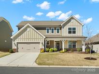 Beautiful two-story home with a covered porch, attached garage, and manicured front lawn under a bright sky at 5532 Muckross Ln, Fort Mill, SC 29707