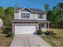 Charming two-story home with stone accents, vinyl siding, a white garage door and well-manicured front yard at 9112 Avery Meadows Dr, Charlotte, NC 28216