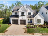 Beautiful new construction farmhouse-style home featuring a two-car garage and a landscaped front yard at 14013 Pinoli Pine Cir, Huntersville, NC 28078