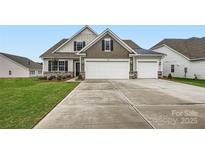 Charming home featuring a three car garage, stone accents, landscaping, and a well-manicured lawn at 1541 Croydon St, Indian Land, SC 29707
