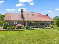 Charming brick home with a red metal roof, covered porch, and well-manicured lawn at 2251 Old Applewood Ln # 9, Iron Station, NC 28080