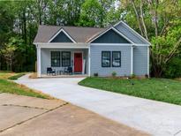 Charming home featuring a well-manicured lawn, inviting front porch, and a vibrant red front door at 2302 Jordi Way, Charlotte, NC 28213