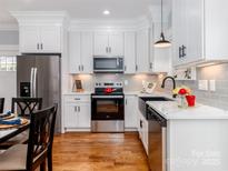 Bright kitchen features stainless steel appliances, white cabinetry, subway tile backsplash, and hardwood flooring at 2302 Jordi Way, Charlotte, NC 28213