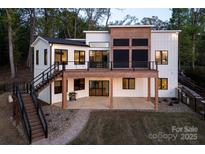 Modern home featuring a deck, white siding, black trim, outdoor stairs and a stone path at 264 Fairway Shores Rd, Mount Gilead, NC 27306