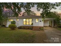 Charming one-story home with white brick, new windows, front yard with green lawn and landscaped features at 3108 Anne St, Charlotte, NC 28205