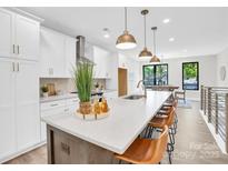 Modern kitchen features a large island, white cabinets, stainless steel appliances, and beautiful pendant lighting at 3449 Byrnes St, Charlotte, NC 28205