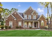 Stately brick home featuring a well-manicured lawn and inviting front porch with elegant architectural detailing at 551 Hemmings Nw Pl, Concord, NC 28027