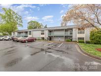 A two-story condo building features muted grey siding with a parking lot and car on a cloudy day at 10967 Harrowfield Rd, Charlotte, NC 28226