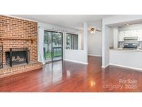 Bright living room featuring hardwood floors and sliding glass door to balcony with view to kitchen at 10967 Harrowfield Rd, Charlotte, NC 28226