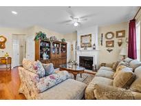 Bright living room offers a fireplace, hardwood floors, ceiling fan, and classic design at 14869 Santa Lucia Dr, Charlotte, NC 28277