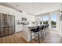 Bright kitchen featuring white cabinets, stainless steel appliances, and a large center island with bar seating at 5051 Westmead Ln, Charlotte, NC 28262