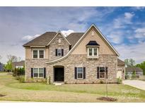 Charming two-story home featuring a stone facade, well-manicured lawn, and classic architectural details at 7157 Sumters Camp Trl, Indian Land, SC 29707