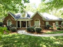 Traditional brick home with arched windows, manicured shrubs, and a walkway leading to a covered front entrance at 9101 Oak Bluff Ct, Marvin, NC 28173