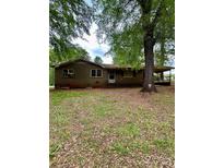 Single story home with a brick exterior and covered parking surrounded by mature trees in the front yard at 204 Long Creek Rd, Bessemer City, NC 28016