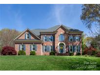 Stunning brick two-story home with manicured lawn and blue shutters on a sunny day at 3010 Lakewood Edge Dr, Charlotte, NC 28269