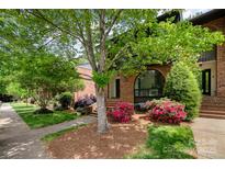 Brick townhome featuring a well-maintained yard, lush landscaping, and a charming arched window at 5807 Sharon Rd # A, Charlotte, NC 28210