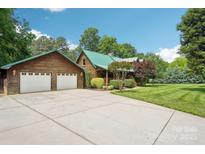 Expansive driveway leading to a charming log home with a matching detached two-car garage at 10583 Earnhardt Lake Rd, Davidson, NC 28036