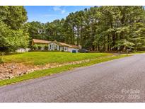 Charming single-story home with lush green lawn and mature trees providing shade and curb appeal at 130 Overcreek Rd, Mooresville, NC 28117