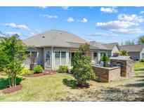 A beautiful outdoor living space with lush lawn, brick fireplace, and seating area at 17315 Langston Dr, Charlotte, NC 28278