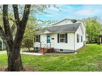 Charming white house with a landscaped front yard, blue front door, and mature tree at 390 15Th Ne Ave, Hickory, NC 28601