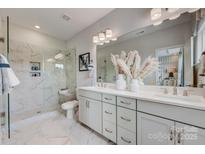 Modern bathroom featuring a glass-enclosed shower with marble tile and dual sink vanity with white cabinetry at 5055 Westmead Ln, Charlotte, NC 28262