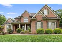 Charming brick home with manicured landscaping, symmetrical design, and inviting covered front porch at 7600 Brookmont Ln, Waxhaw, NC 28173