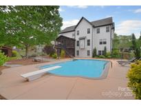 Inviting backyard pool area with a diving board, landscaping, and a spacious patio, perfect for outdoor relaxation at 1811 Robbins Meadows Dr, Waxhaw, NC 28173