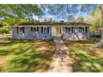 Charming single-story home with a gray brick exterior, black shutters, and a bright yellow front door at 1860 Rosemont St, Salisbury, NC 28144