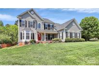 Charming two-story home boasts a well-manicured lawn, complemented by black shutters and a striking red front door at 1930 Southridge Dr, Belmont, NC 28012