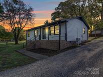 Charming single-story home featuring white siding, brick foundation, and a covered porch with black railings at 4903 Walt Gay Rd, Monroe, NC 28112