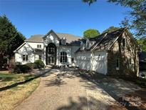 A stunning two-story home with stone and white exterior, features a three-car garage and arched entry at 5517 Mountain Point Ln, Charlotte, NC 28216
