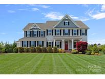 Beautiful two-story home with a manicured lawn, lush landscaping, and a welcoming red front door at 708 Brookmeade Dr, Waxhaw, NC 28173